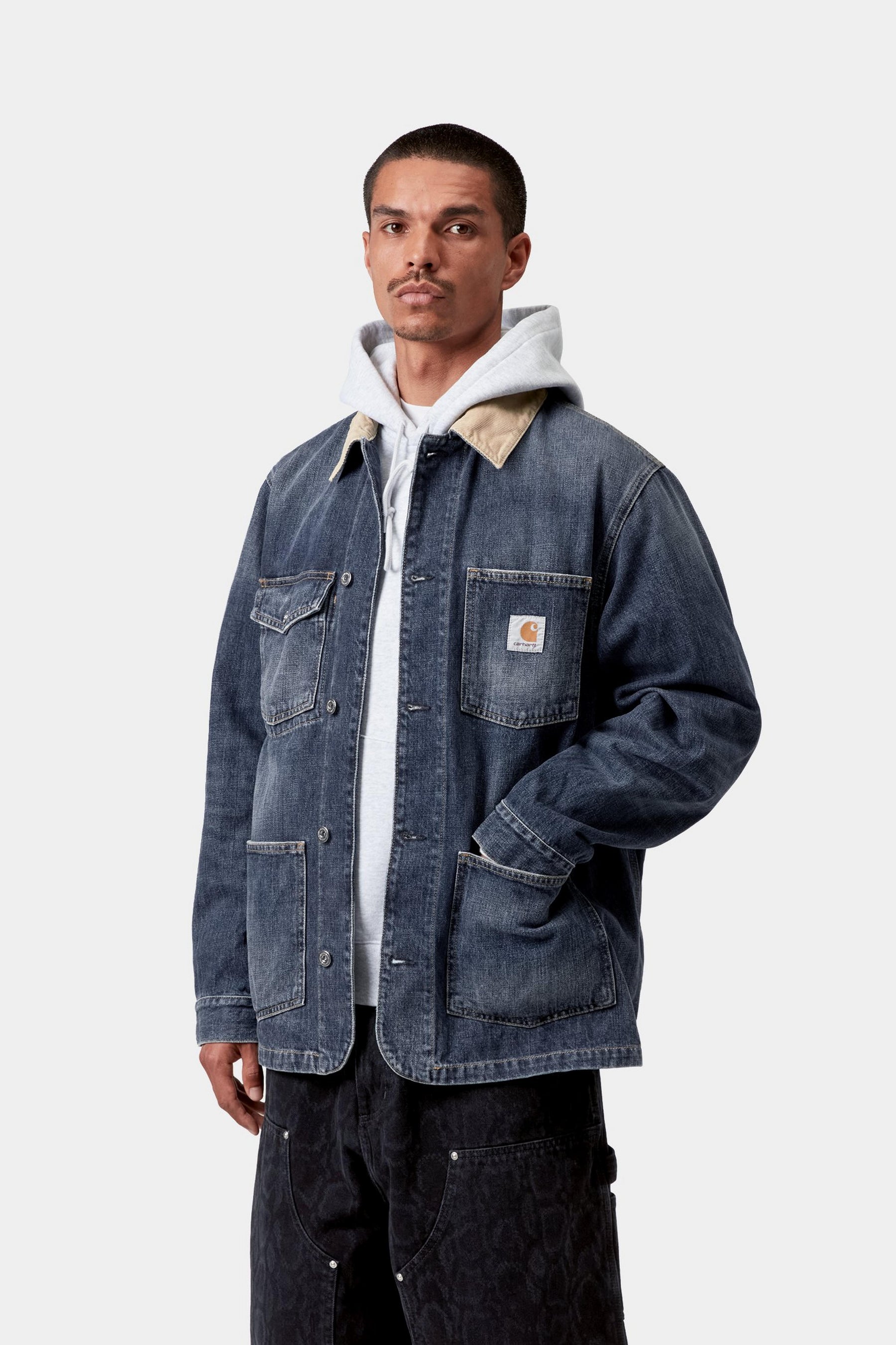 Model wearing a men's blue and brown washed chore coat with relaxed workwear styling