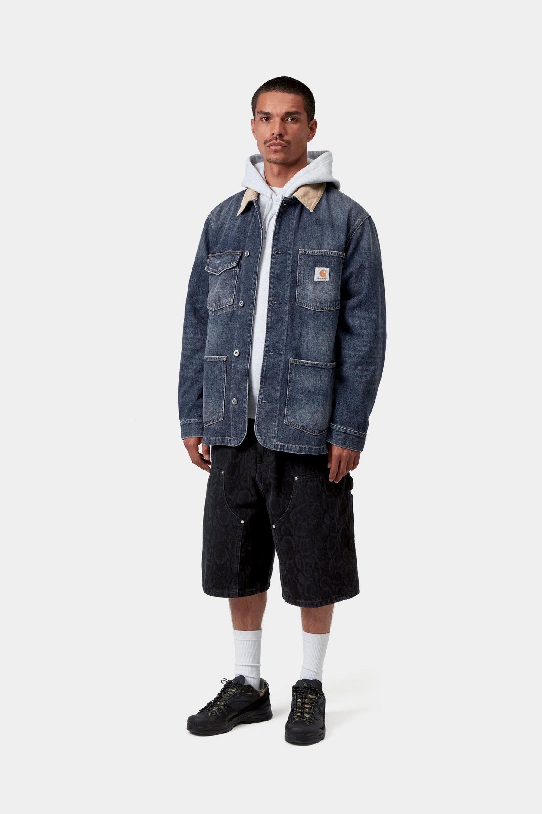 Model wearing a washed blue and brown chore jacket showing its utility-inspired silhouette