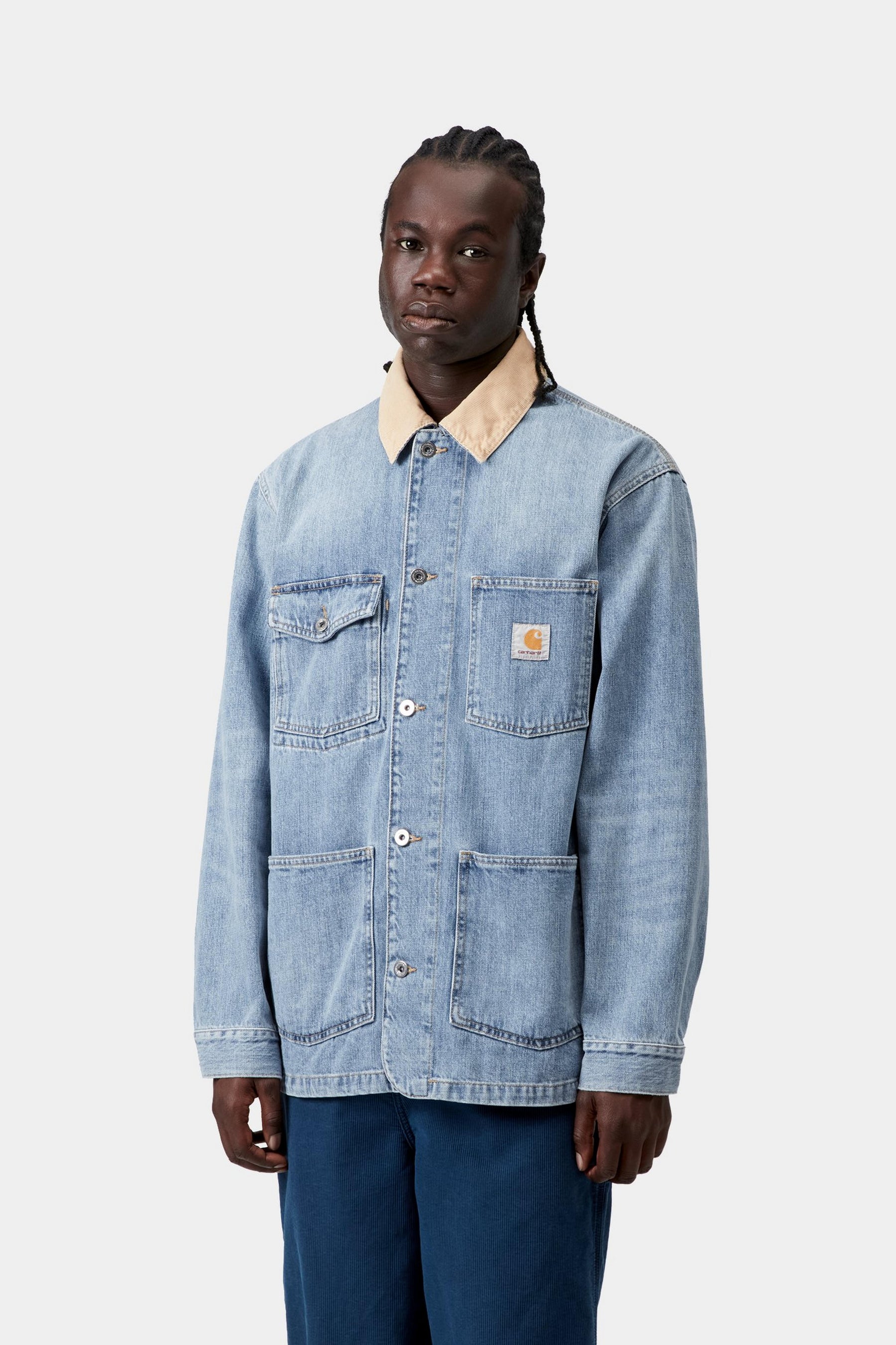 Model wearing a burst washed blue and dusty brown chore jacket in a casual layered look